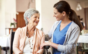 Caregiver assisting happy senior woman in wheelchair