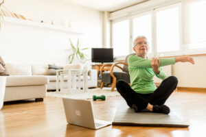 Senior woman exercising at home using an online trainer service.