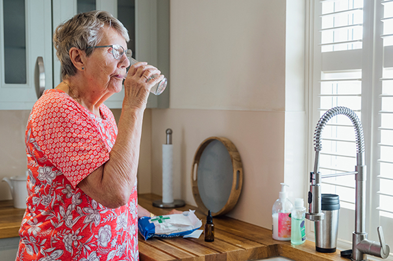 senior-lady-drinking-water-in-kitchen