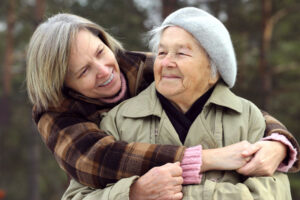 An adult woman hugs her elderly mother. Supporting caregivers is an important step in providing better senior care.